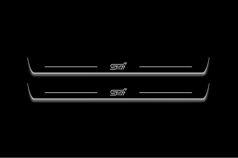 Two long door sill plates with STI lettering and edges illuminated in white, straight-on view on a dark background.