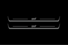 Two long door sill plates with STI lettering and edges illuminated in white, straight-on view on a dark background.