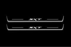 Two long door sill plates with SXT lettering and edges illuminated in white, straight-on view on a dark background.