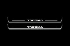 Two long door sill plates with Tacoma lettering and edges illuminated in white, straight-on view on a dark background.