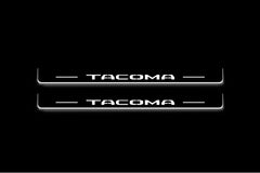 Two long door sill plates with Tacoma lettering and edges illuminated in white, straight-on view on a dark background.