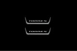 Two short door sill plates with Torres lettering and edges illuminated in white, straight-on view on a dark background.