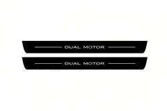 Catalogue illustration of two front black Matte PRO LED door sill plates with illuminated Dual Motor lettering for Tesla Model Y; dimensions are selected during manufacture.