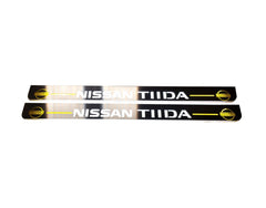 Two long reflective door sill plates with Nissan Tiida lettering and yellow Nissan emblems at the ends.