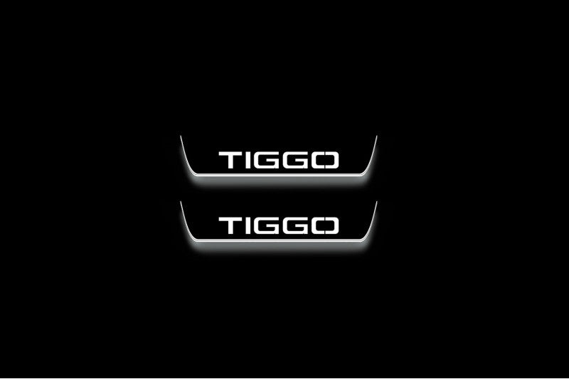 Two short door sill plates with Tiggo lettering and edges illuminated in white, straight-on view on a dark background.