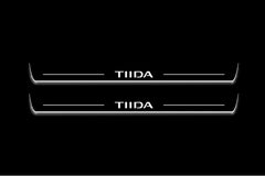 Two long door sill plates with Tiida lettering and edges illuminated in white, straight-on view on a dark background.