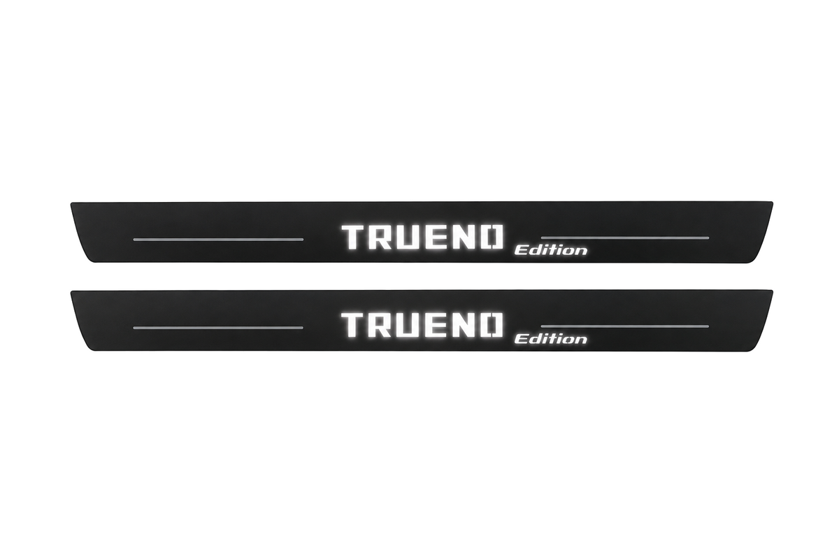 Catalogue illustration of two black Matte PRO front door sill plates with white TRUENO and lowercase italic edition lettering and thin lines illuminated only on the top surface. Rear plates for FRONT+REAR are not pictured; final dimensions are selected for the vehicle during manufacture.