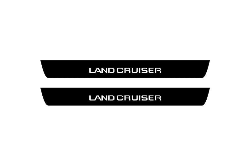 Catalog illustration of two black front door sill plates with Land Cruiser lettering.