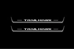 Two long door sill plates with Trailhawk lettering and edges illuminated in white, straight-on view on a dark background.