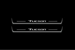 Two long door sill plates with Tucson lettering and edges illuminated in white, straight-on view on a dark background.