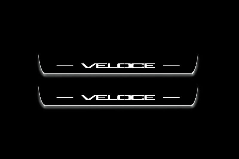 Two long door sill plates with Veloce lettering and edges illuminated in white, straight-on view on a dark background.