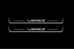 Two long door sill plates with Vignale lettering and edges illuminated in white, straight-on view on a dark background.