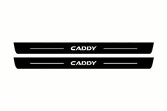 Catalogue illustration of two front black Matte PRO LED door sill plates with illuminated Caddy lettering for Volkswagen Caddy Van SB; dimensions are selected during manufacture.