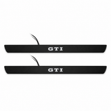 Catalogue illustration of two black Matte PRO front door sill plates with white GTI lettering illuminated only on top. Edges are unlit; rear plates for FRONT+REAR are not pictured. Final dimensions are selected for Golf Mk8 GTI during manufacture.
