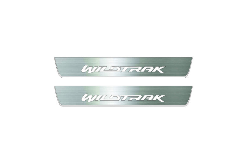 Two short silver-finished door sill plates with Wildtrak lettering on a light background, straight-on view.