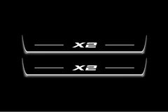 Two long door sill plates with X2 lettering and edges illuminated in white, straight-on view on a dark background.