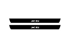 Catalog illustration of two black front door sill plates with X5 lettering.