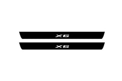 Catalog illustration of two black front door sill plates with X6 lettering.