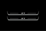 Two long door sill plates with X7 lettering and edges illuminated in white, straight-on view on a dark background.