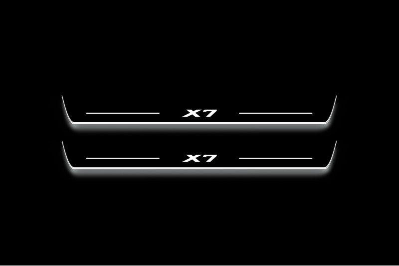 Two long door sill plates with X7 lettering and edges illuminated in white, straight-on view on a dark background.