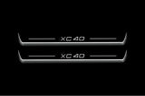 Two long door sill plates with XC40 lettering and edges illuminated in white, straight-on view on a dark background.