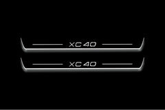 Two long door sill plates with XC40 lettering and edges illuminated in white, straight-on view on a dark background.