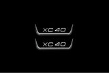 Two short door sill plates with XC40 lettering and edges illuminated in white, straight-on view on a dark background.