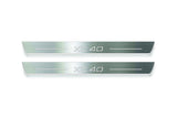 Two long silver-finished door sill plates with XC40 lettering on a light background, straight-on view.