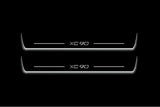Two long door sill plates with XC90 lettering and edges illuminated in white, straight-on view on a dark background.