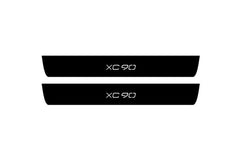 Catalog illustration of two black front door sill plates with XC90 lettering.