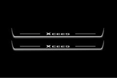 Two long door sill plates with XCeed lettering and edges illuminated in white, straight-on view on a dark background.