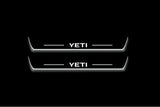 Two long door sill plates with Yeti lettering and edges illuminated in white, straight-on view on a dark background.