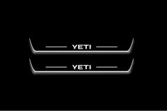 Two long door sill plates with Yeti lettering and edges illuminated in white, straight-on view on a dark background.