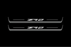 Two long door sill plates with ZR2 lettering and edges illuminated in white, straight-on view on a dark background.